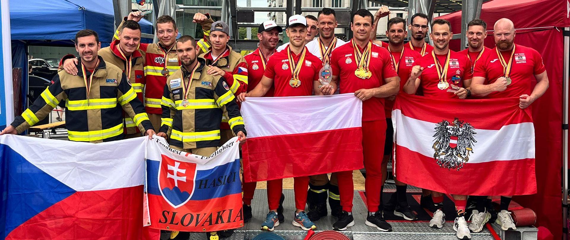 Zawodnicy zawodów i Reprezentacja Polski na zawodach 18 Firefighter Combat Challenge Berlin. Zawodnicy trzymają przed sobą flagi panstowe.