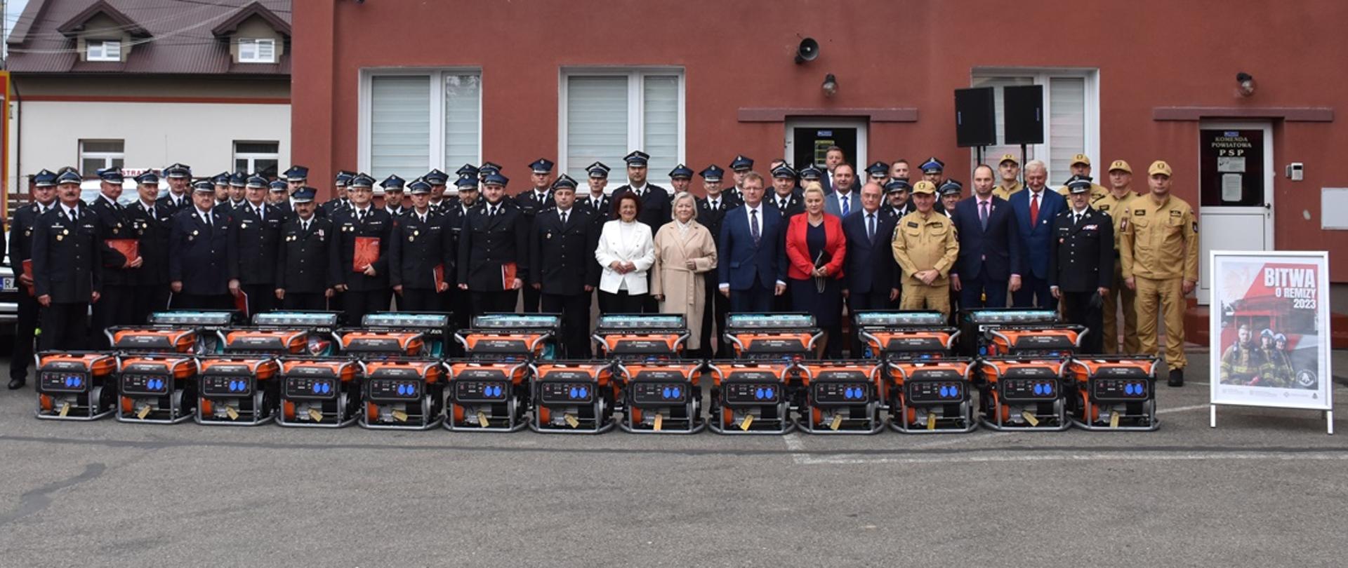 Zdjęcie zrobione na zewnątrz, czas uroczystej zbiórki z okazji przekazania agregatu prądotwórczych jednostkom Ochotniczych Straży Pożarnych.