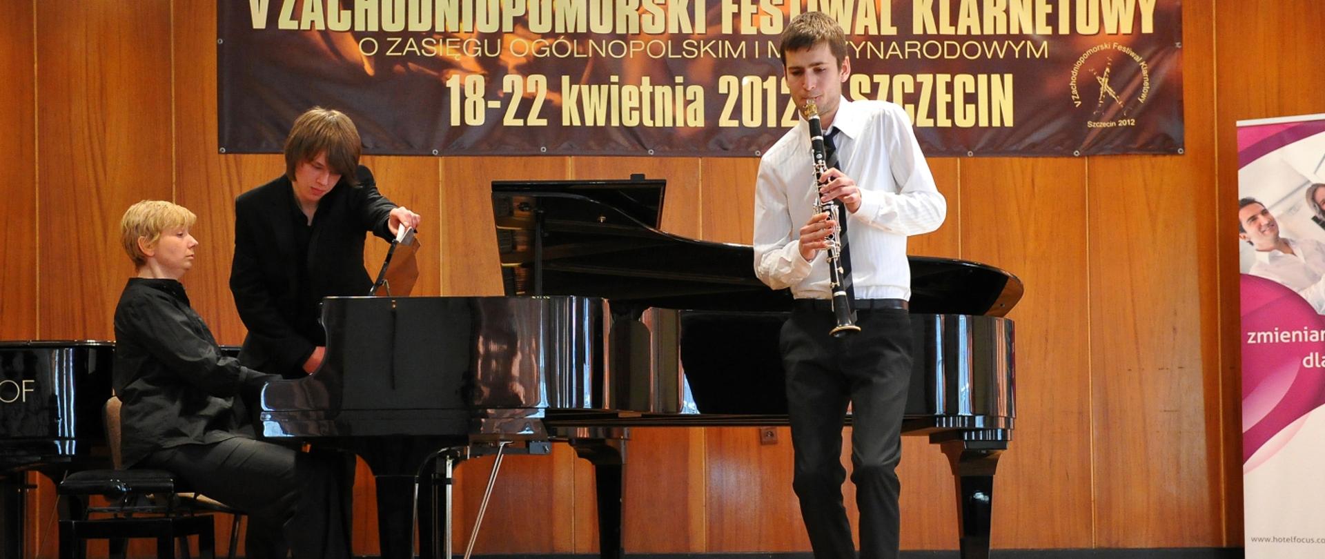 Grafika przedstawia odoby grające na klarnecie i fortepianie