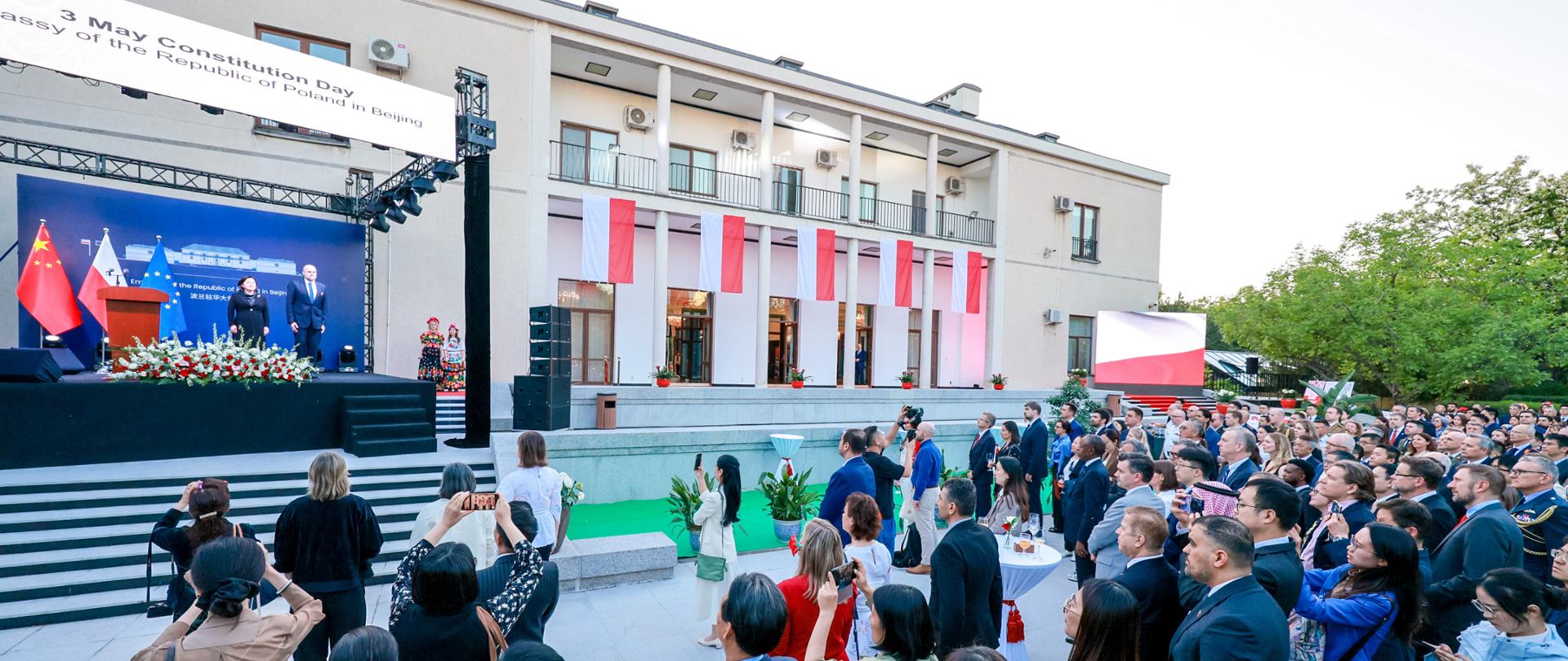 Goście pod sceną, na której stoją Ambasador Jakub Kumoch oraz Wiceminister SZ ChRL Hua Chunying