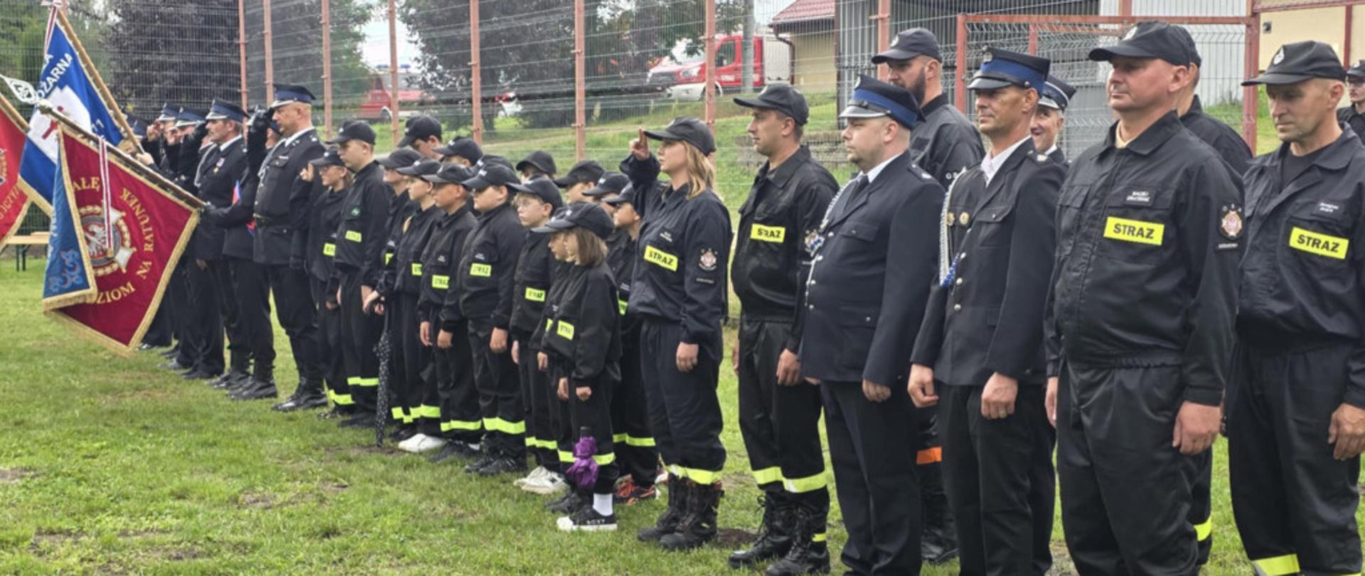 Strażacy stoją podczas uroczystości.