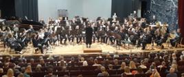 Orkiestra instrumentów dętych - koncert finałowy w sali koncertowej Helsingen Konservatorio, z przodu widać widownię, na estradzie liczna grupa muzyków na różnych instrumentach dętych