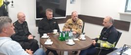 Na zdjęciu widocznych jest 3 funkcjonariuszy PSP oraz 2 przedstawicieli Gaz-Stystem S.A. siedzących przy okrągłym stole kawowym. Od lewej: Zastępca Dyrektora Pionu Terminalu LNG Arkadiusz Piotrowski, Komendant Miejski PSP w Świnoujściu st. kpt. Marek Wieczorek, Zastępca Zachodniopomorskiego Komendanta Wojewódzkiego st. bryg. Kazimierz Lesisz, Zachodniopomorski Komendant Wojewódzki PSP nadbryg. Jarosław Tomczyk, Dyrektor Pionu Terminalu LNG Grzegorz Błędowski. 
