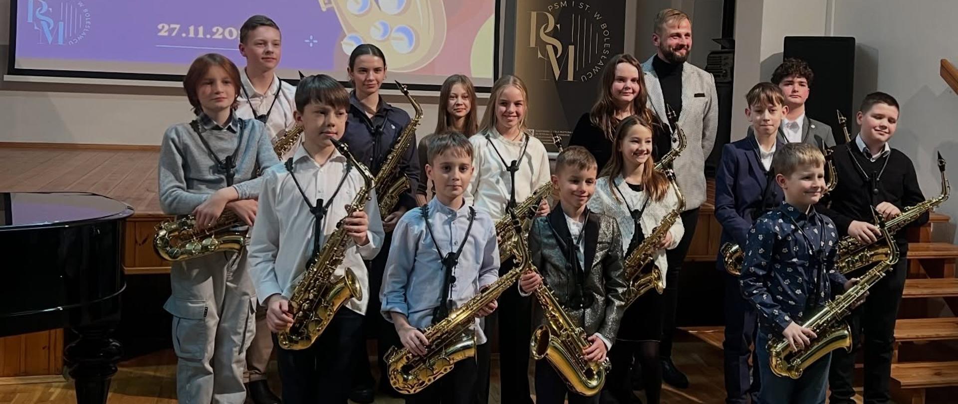 Zdjęcie przedstawiające wykonawców popisu klasy saksofonu mgr Mateusza Boducha, który odbył się 27 listopada 2025 r. w auli szkoły.