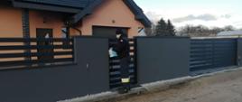Widać strażaka z dostarczaną ulotką przy wejściu