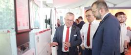 Minister funduszy i polityki regionalnej Grzegorz Puda zwiedza wystawę Międzynarodowych Energetycznych Targów Bielskich ENERGETAB, minister stoi przy urządzeniu w towarzystwie dwóch mężczyzn
