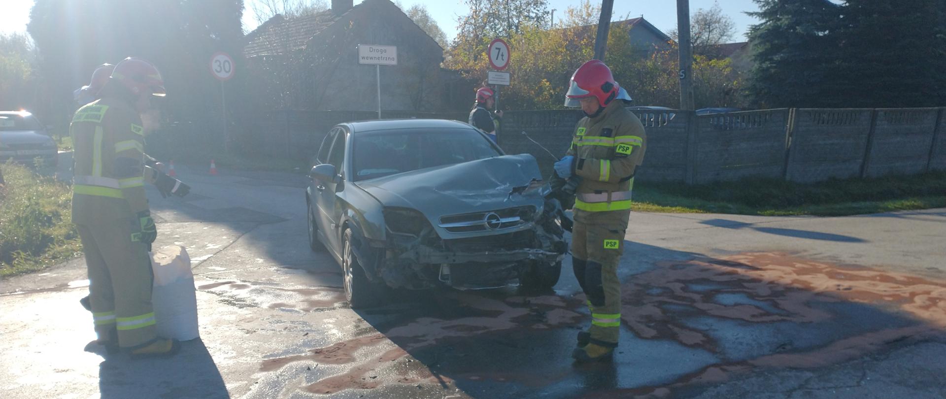 Strażacy posypują sorbentem rozlane płyny eksploatacyjne