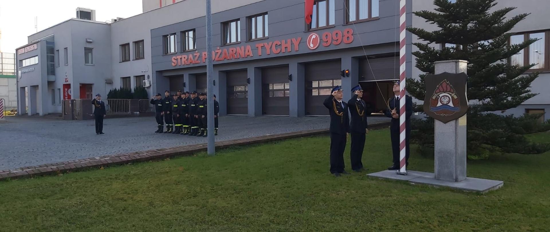 Strażacy podnoszą flagę podczas której odśpiewany został hymn narodowy
