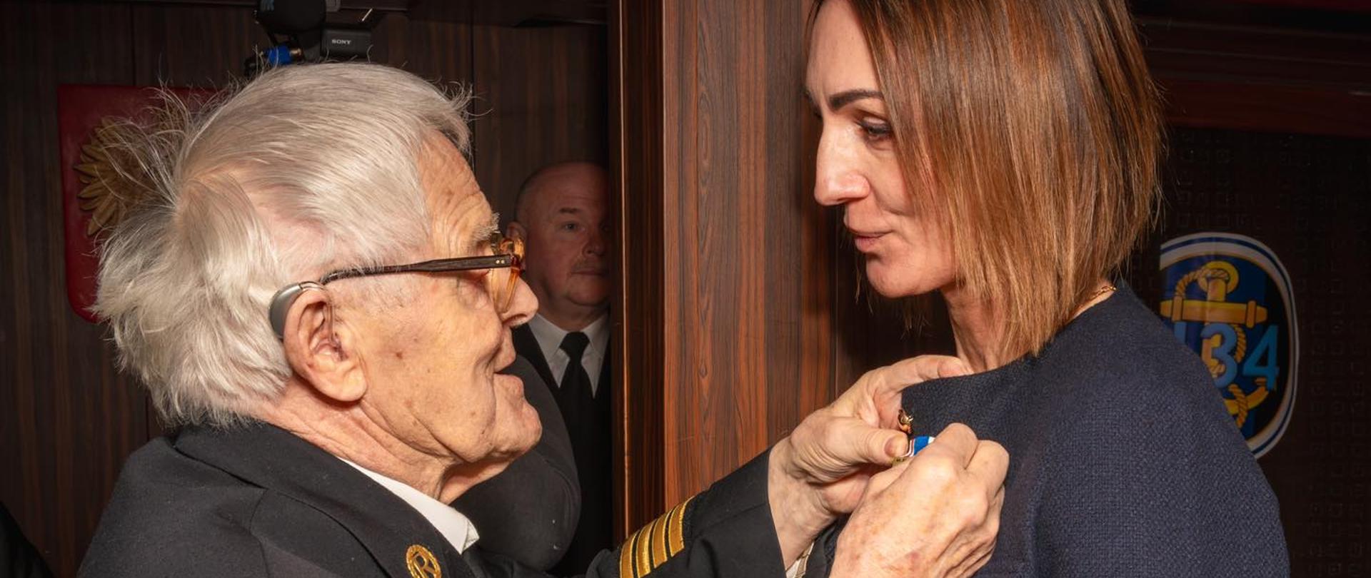 Mężczyzna w mundurze przypina medal kobiecie (wojewodzie pomorskiej)