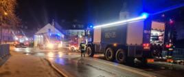 Na zdjęciu widać samochody ratowniczo - gaśnicze w tym Wojskową Straż Pożarną, prowadzące linie zasilającą do gaszenia pożaru.