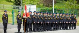 Na zdjęciu widoczny pododdział strażaków z Komendy powiatowej Straży Pożarnej w Gorlicach oraz poczet sztandarowy podczas apel z okazji Dnia Strażaka 2023 w KP PSP w Gorlicach . Strażacy w umundurowaniu galowym koloru granatowego w czapkach rogatywkach ze sznurem.
