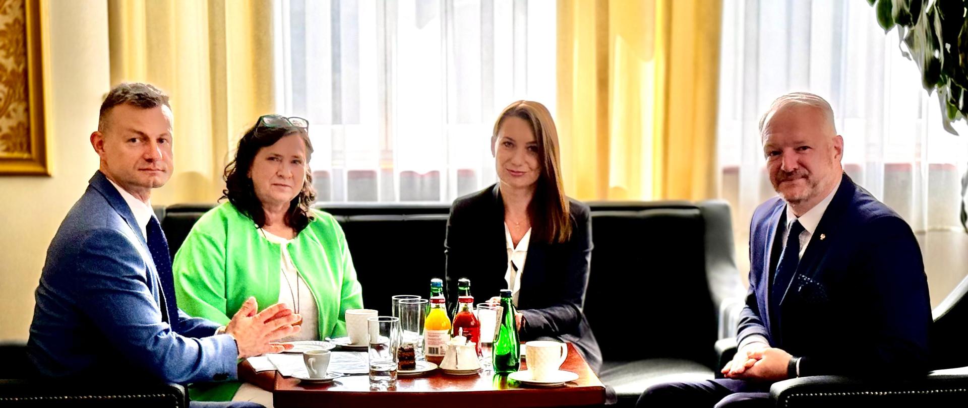 Spotkanie w gabinecie Wojewody Warmińsko-Mazurskiego Radosława Króla dot. spraw cudzoziemców, w dniu 22 sierpnia 2024 r. Przy stole siedzą 4 osoby i rozmawiają. 