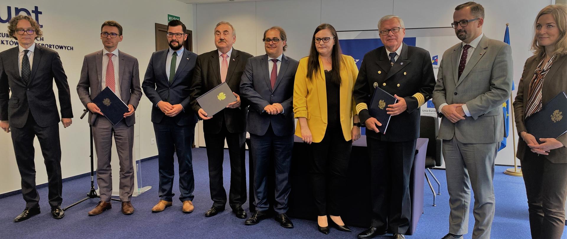 Zdjęcie grupowe, na zdjęciu 9 osób, minister Małgorzata Jarosińska Jedynak, minister
Marek Gróbarczyk, minister Marcin Horała, dyrektor
Sylwia Cieślak-Wilk, wicewojewoda
Marek Subocz, prezent Michał Przepiera, Wiesław Piotrzkowski - Dyrektor Urzędu Morskiego w Gdyni i
Kazimierz Drzazga wiceprezes ds. Infrastruktury. Zarząd Morskich Portów Szczecin i Świnoujście S.A.