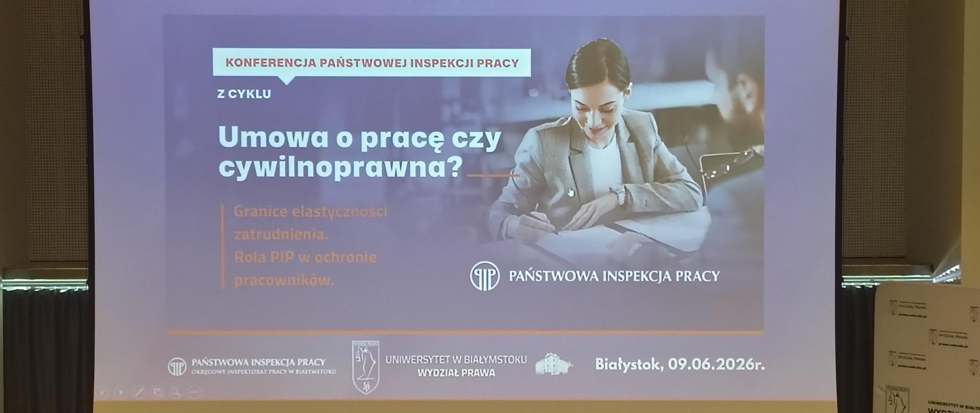 Ekran z prezentacją umieszczony przed stołem.