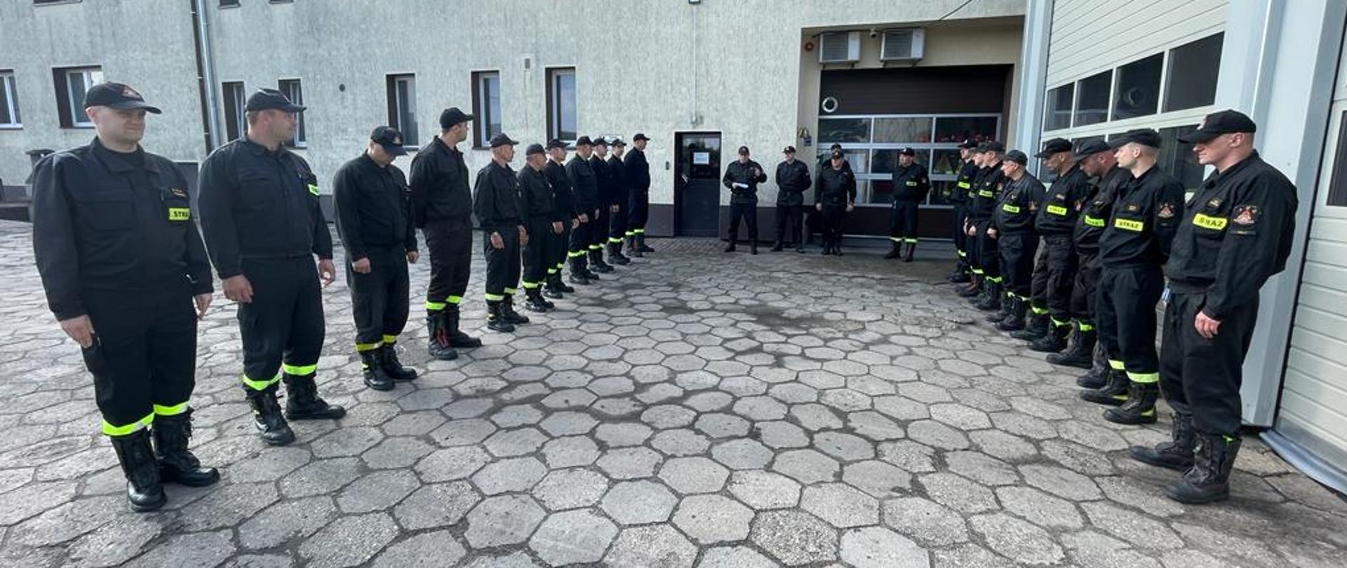 Zdjęcia przedstawiają strażaków PSP podczas uroczystej zbiórki z okazji wręczenia decyzji wyróżnionemu strażakowi. Uroczystość odbywa się na zewnątrz, jest jasno i pochmurnie. 