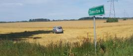 widoczne miejsce zdarzenia, samochód osobowy który wypadł z jezdni i znajduje się na ściernisku