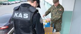 Funkcjonariusz KAS i żołnierz WOT podczas przekazywania alkoholu do dezynfekcji.