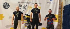 Trzech zawodników z medalami stoi na stopniach podium.