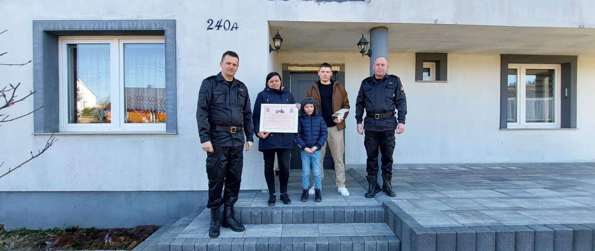 Zdjęcie przedstawiające wręczenie dyplomu z podziękowaniem za pomoc poszkodowanym w wybuchu gazu