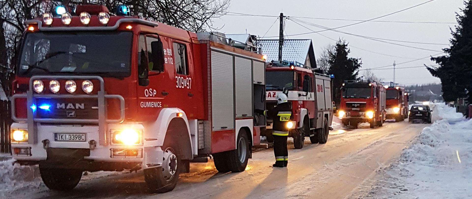 Zdjęcie przedstawia trzy samochody pożarnicze ustawione jeden za drugim na zaśnieżonej drodze.