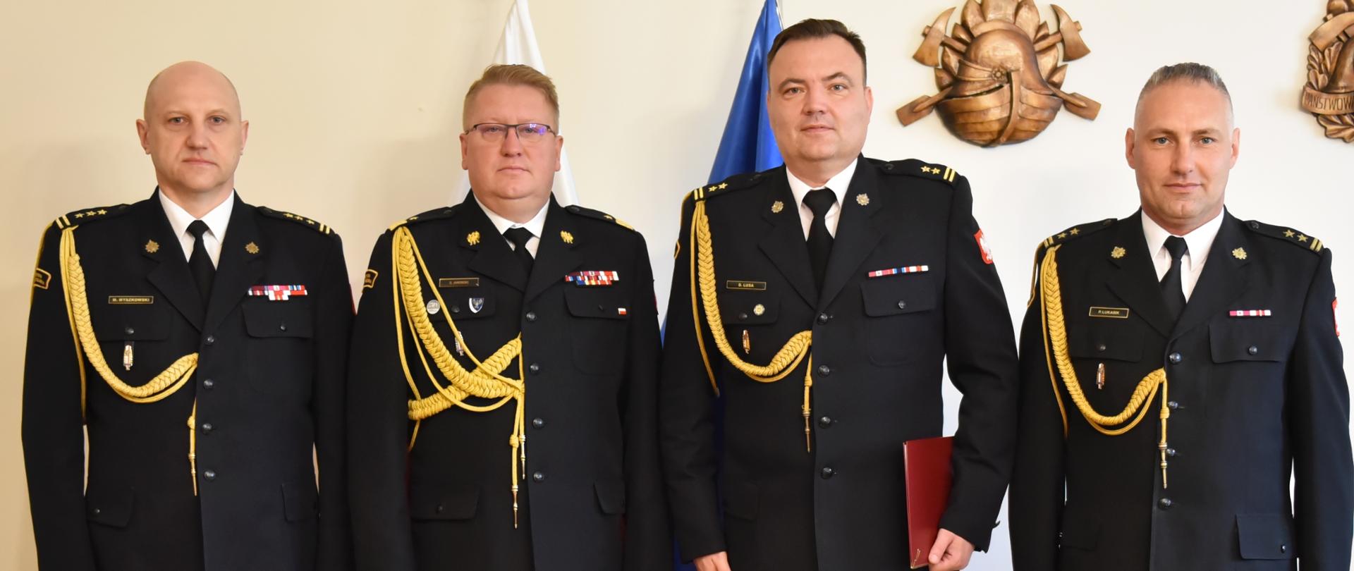 Na zdjęciu 4 oficerów Straży Pożarnej w mundurach wyjściowych w kolorze granatowym 