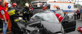 Zdjęcie przedstawia strażaków ćwiczących przy rozbitym samochodzie