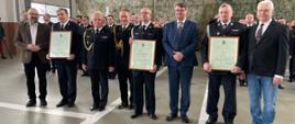 Strażacy trzymający w rękach dokument potwierdzający przyjęcie ich jednostek OSP do KSRG pozują do zdjęcia 