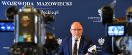 Na pierwszym planie ustawione na konferencji prasowej kamery telewizyjne, na drugim Wojewoda Mazowiecki Zdzisław Sipiera za stołem prezydialnym na tle ścianki wizerunkowej