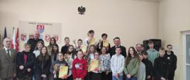 Fotografia przedstawiająca finalistów Powiatowego Turnieju Wiedzy Pożarniczej wraz z Wicestarostą powiatu szydłowieckiego, przedstawicielem Regionalnej Dyrekcji Lasów Państwowych w Radomiu, Komendantem Powiatowym PSP w Szydłowcu oraz Zastępcę Komendanta Powiatowego PSP w Szydłowcu.