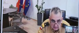 Zastępca komendanta głównego Państwowej Straży Pożarnej uczestnicy w naradzie za pomocą systemu wideokonferencji.