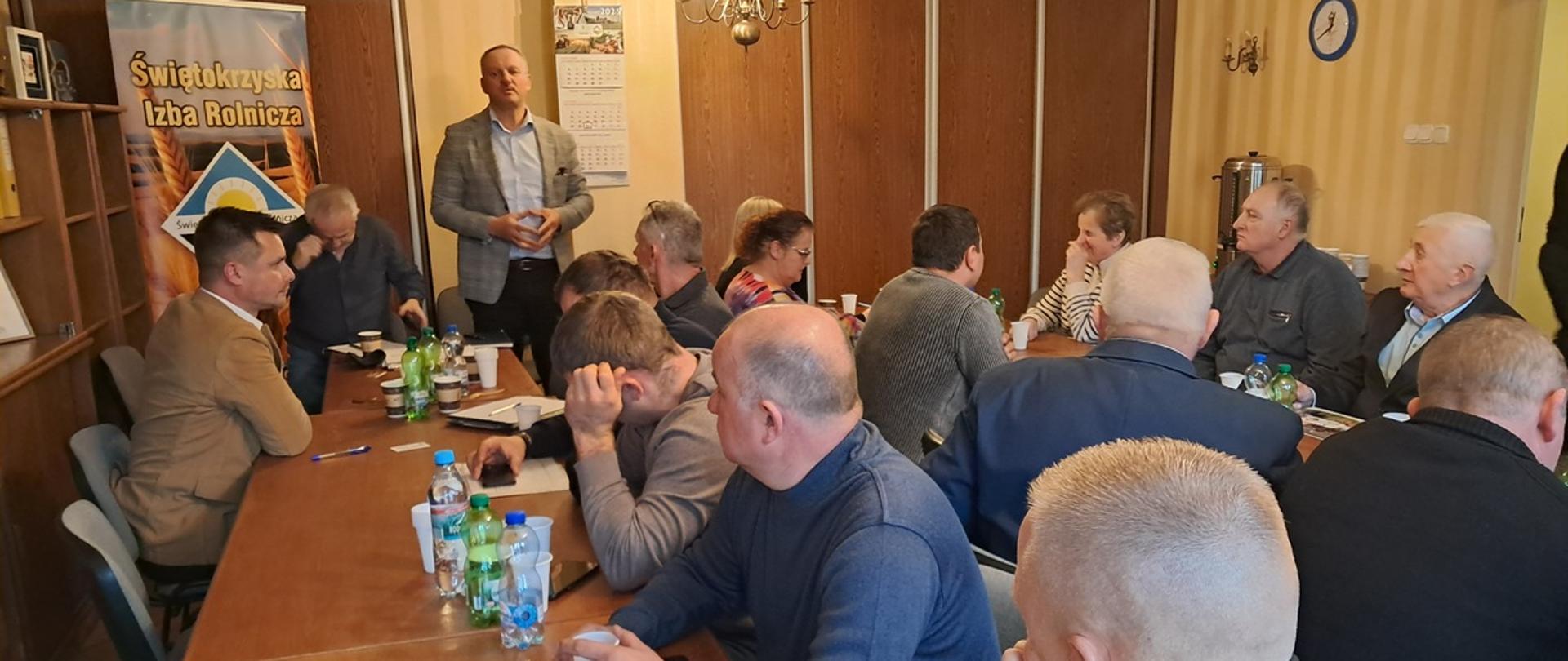 Przemówienie w trakcie zebrania Izby Rolniczej. Kilkanaście osób siedzących przy stołach, jeden mężczyzna stoi na końcu stołu.