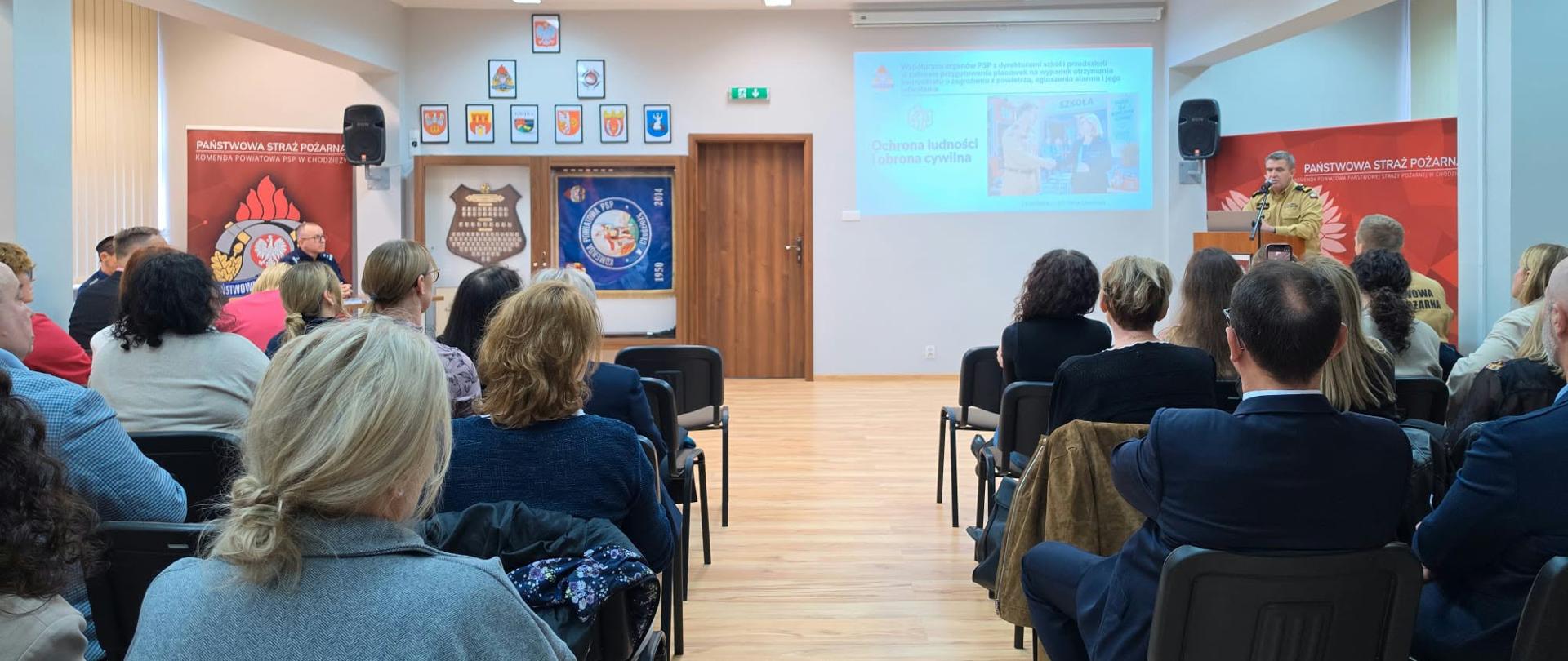 Zdjęcie przedstawia strażaków podczas szkolenia z dyrektorami szkół i przedszkoli.
W tle pomieszczenie.
