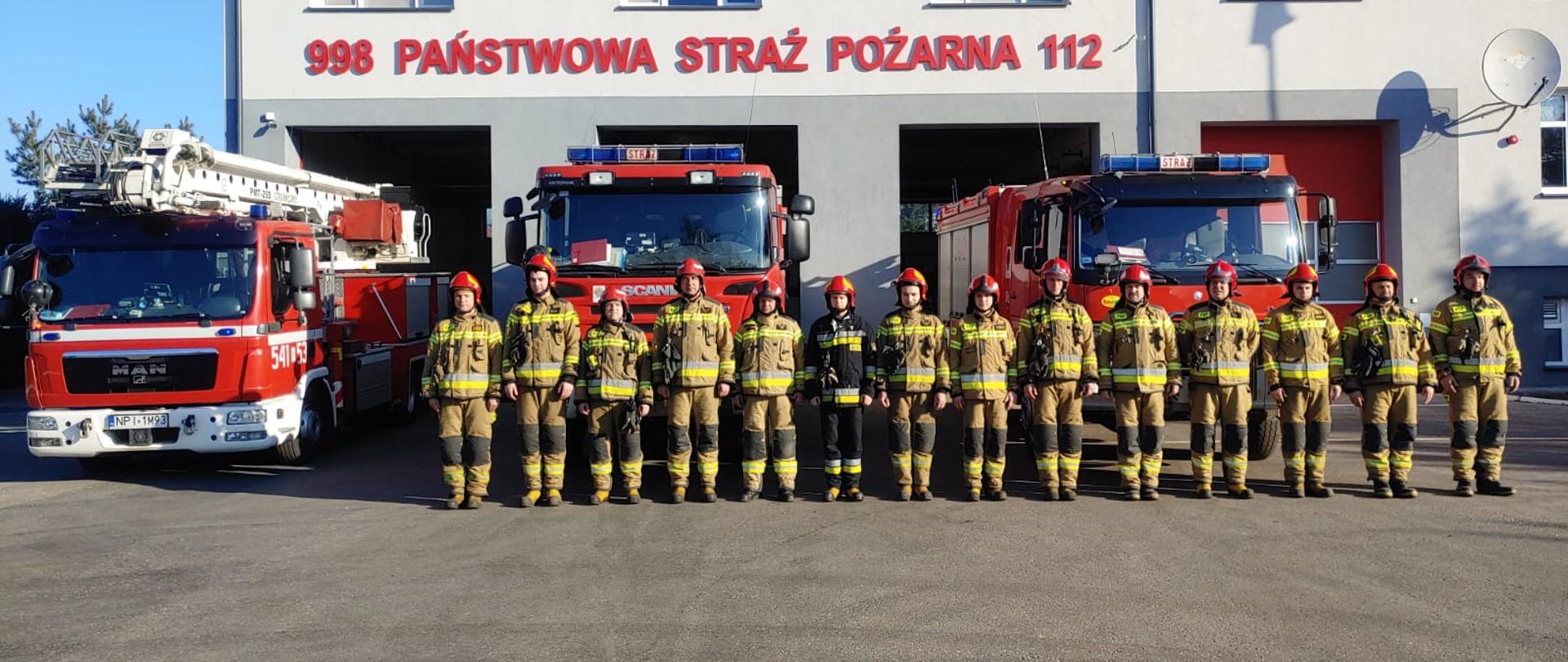 Strażacy stojący przed budynkiem komendy.