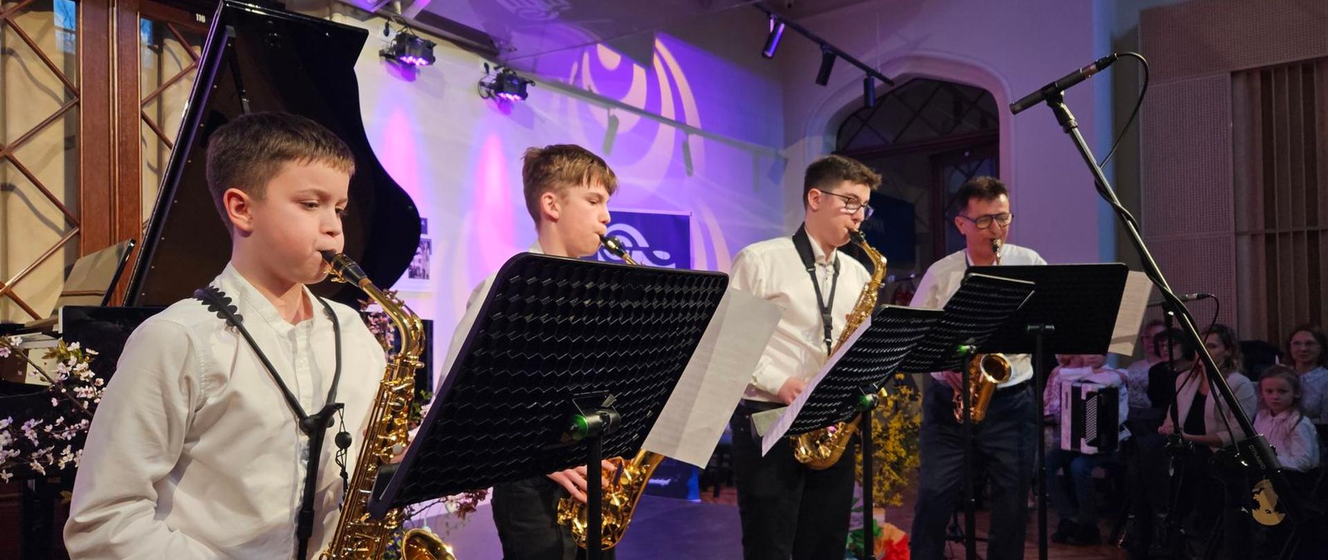 Zdjęcie przedstawia wykonawców podczas koncertu szkolnego "Mistrz i uczeń" w holu Pałacu Radolińskich w Jarocinie.