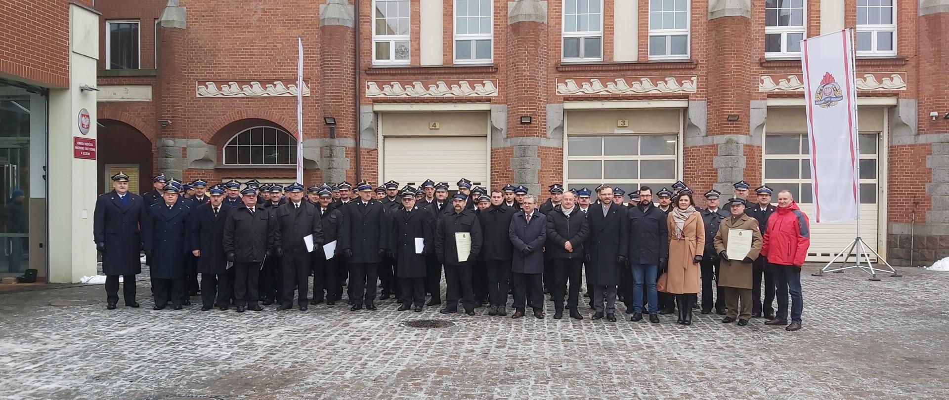 Na zdjęciu widać przedstawicieli Ochotniczych Straży Pożarnych, Wojskowej Straży Pożarnej, Komendantów Miejskich i Powiatowych Państwowej Straży Pożarnej oraz zaproszonych gości pozujących do wspólnego zdjęcia przed budynkiem Komendy Wojewódzkiej PSP w Szczecinie.