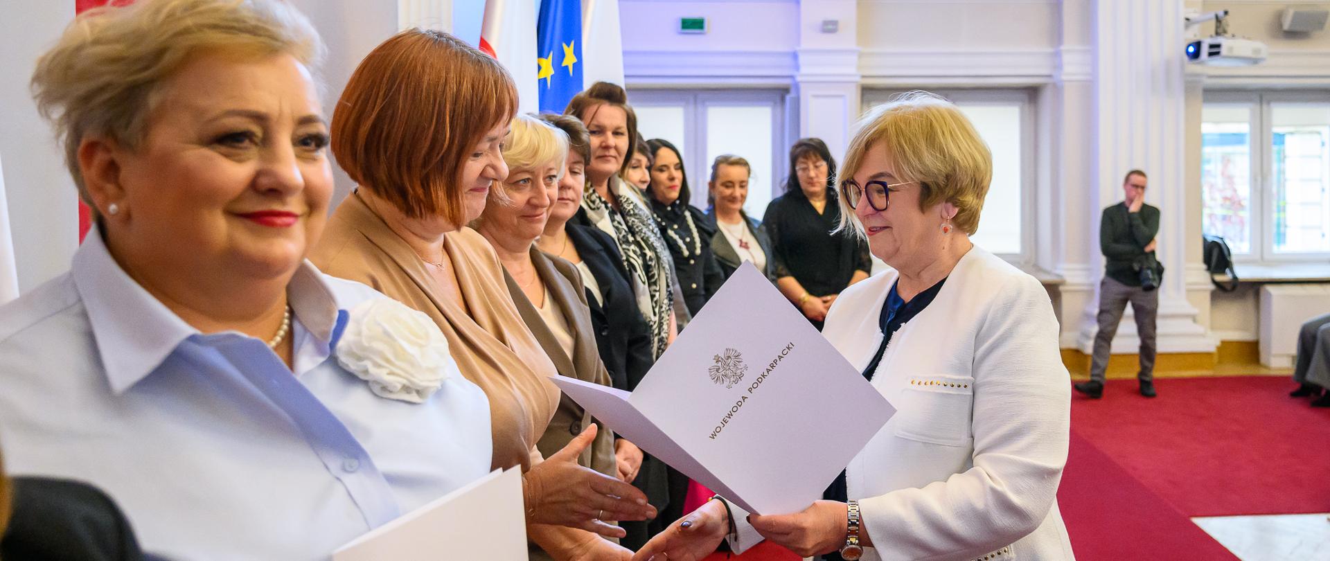 Zdjęcie przedstawia wojewodę podkarpackiego Teresę Kubas-Hul wręczającą listy gratulacyjne podczas uroczystości z okazji Dnia Pracownika Socjalnego