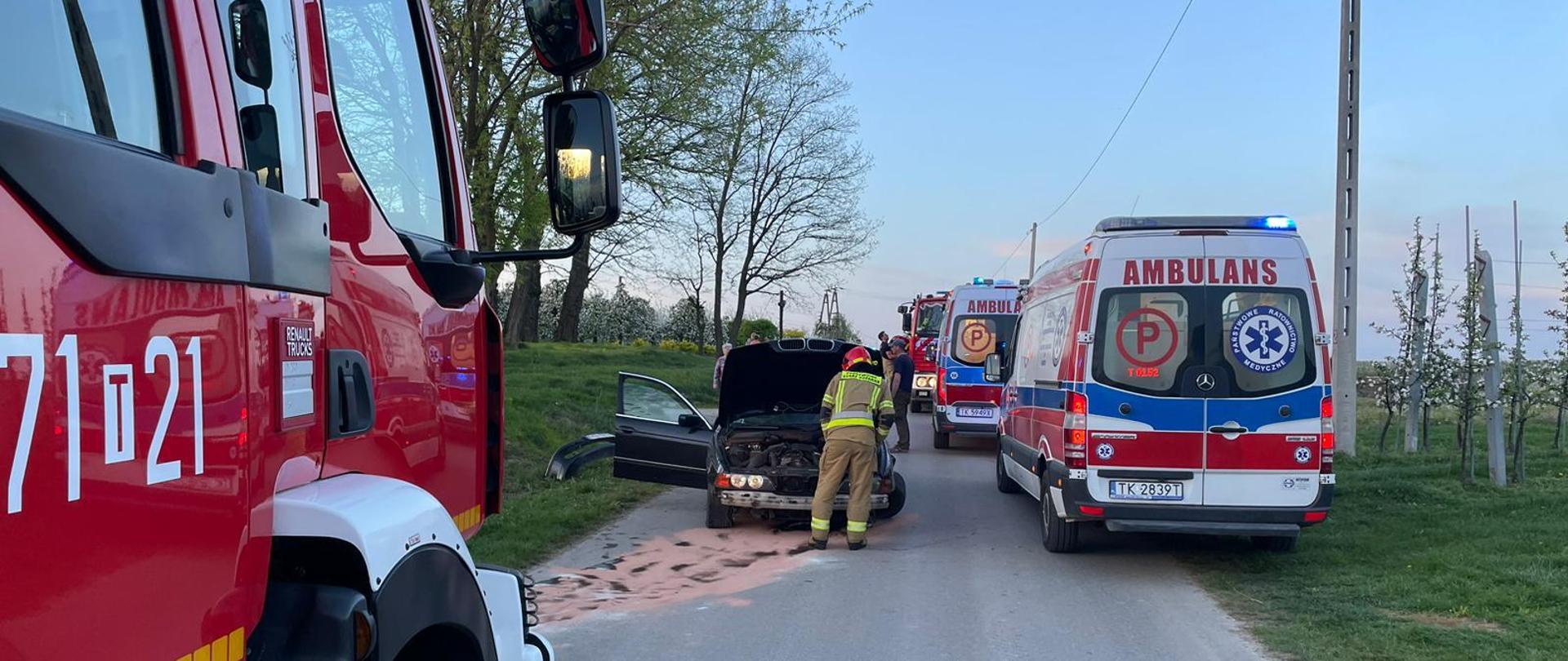 Na zdjęciu widoczny rozbity samochód i strażaka zabezpieczającego zdarzenia.