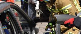 Strażak podczas wycinania sprzętem hydraulicznym drzwi samochodu