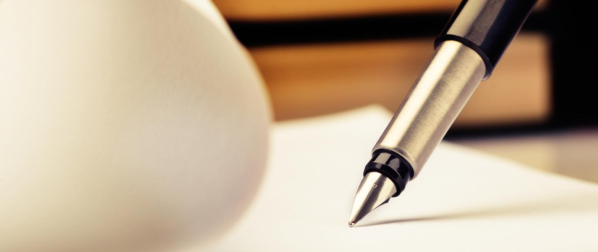 Pióro piszące na kartce papieru.