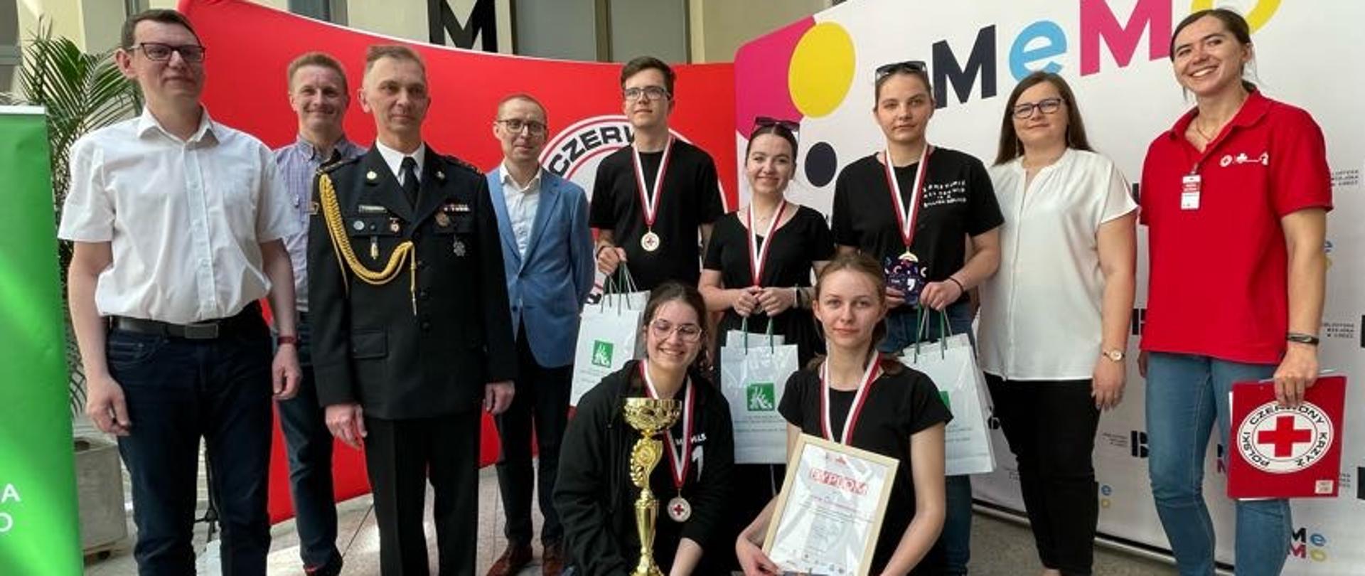 młodzież ze zwycięskiej drużyny oraz st. bryg. Zbigniew Łyszkowicz pozują do zdjęcia 