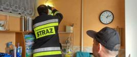 Zdjęcie przedstawia strażaka sprawdzającego kanał wentylacyjny