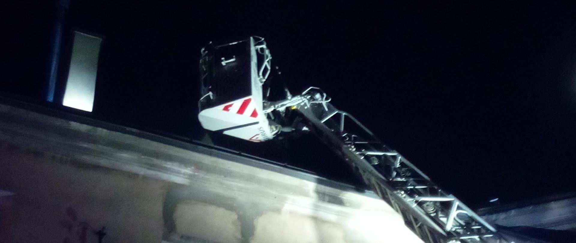 Na zdjęciu pokazano kosz drabiny mechanicznej nad dachem kamienicy gdzie wybuchł pożar.