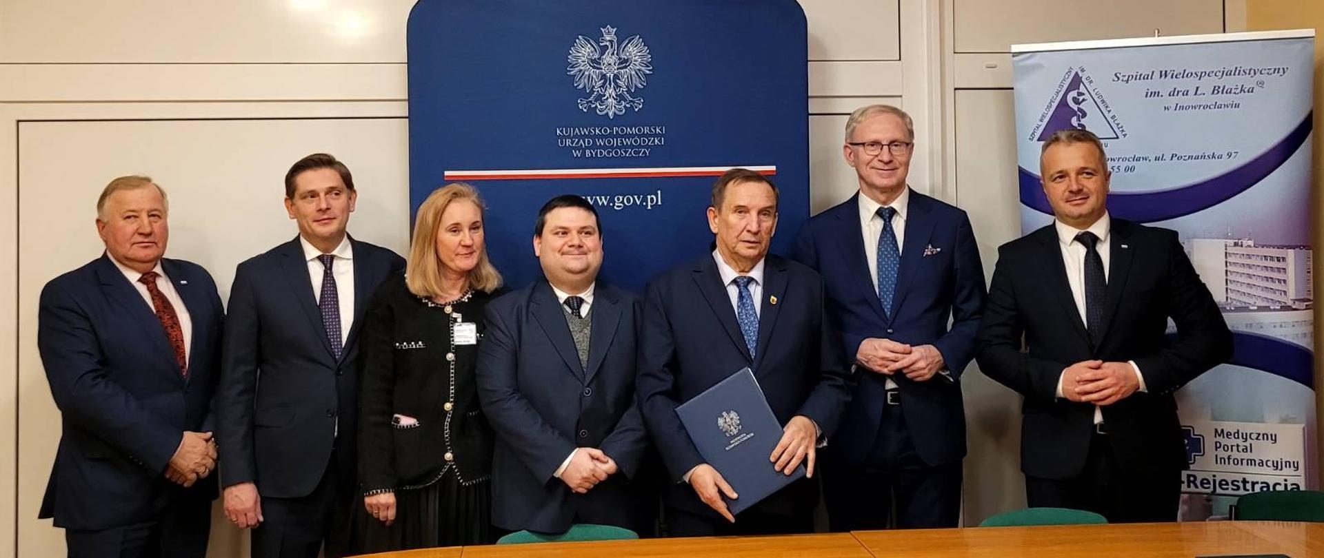 
Grupa ludzi stojąca w sali konferencyjnej
