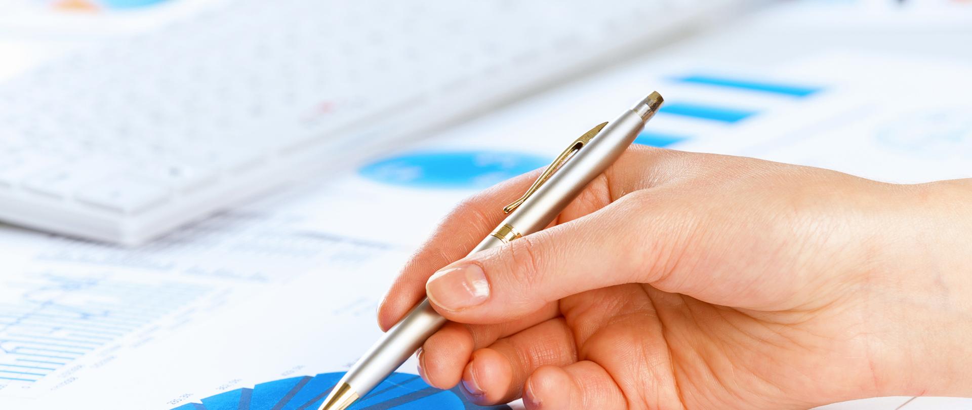 Długopis w dłoni wskazuje na wykres kołowy