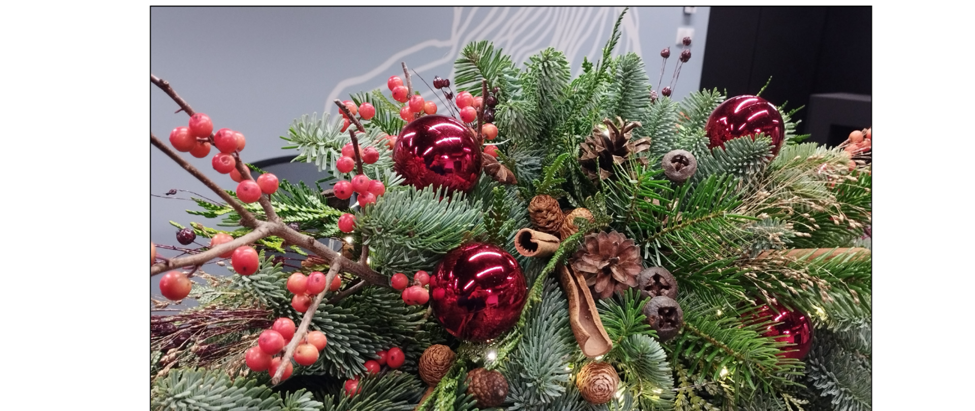 Na białym tle tekst życzen świątecznych w kolorze fioletowym, poniżej zdjęcie stroika świątecznego, pod zdjęciem tekst informujący o koncertach kolędowych 21 i 22 grudnia o godzinie 17.00 w auli.