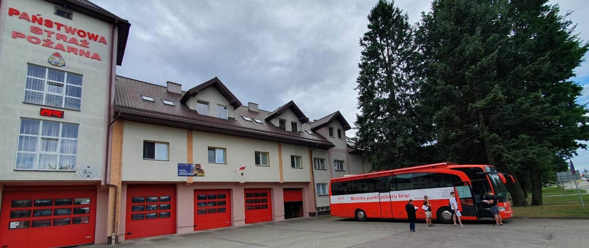 Na tle budynku komendy PSP stoi autobus do mobilnej zbiórki krwi.