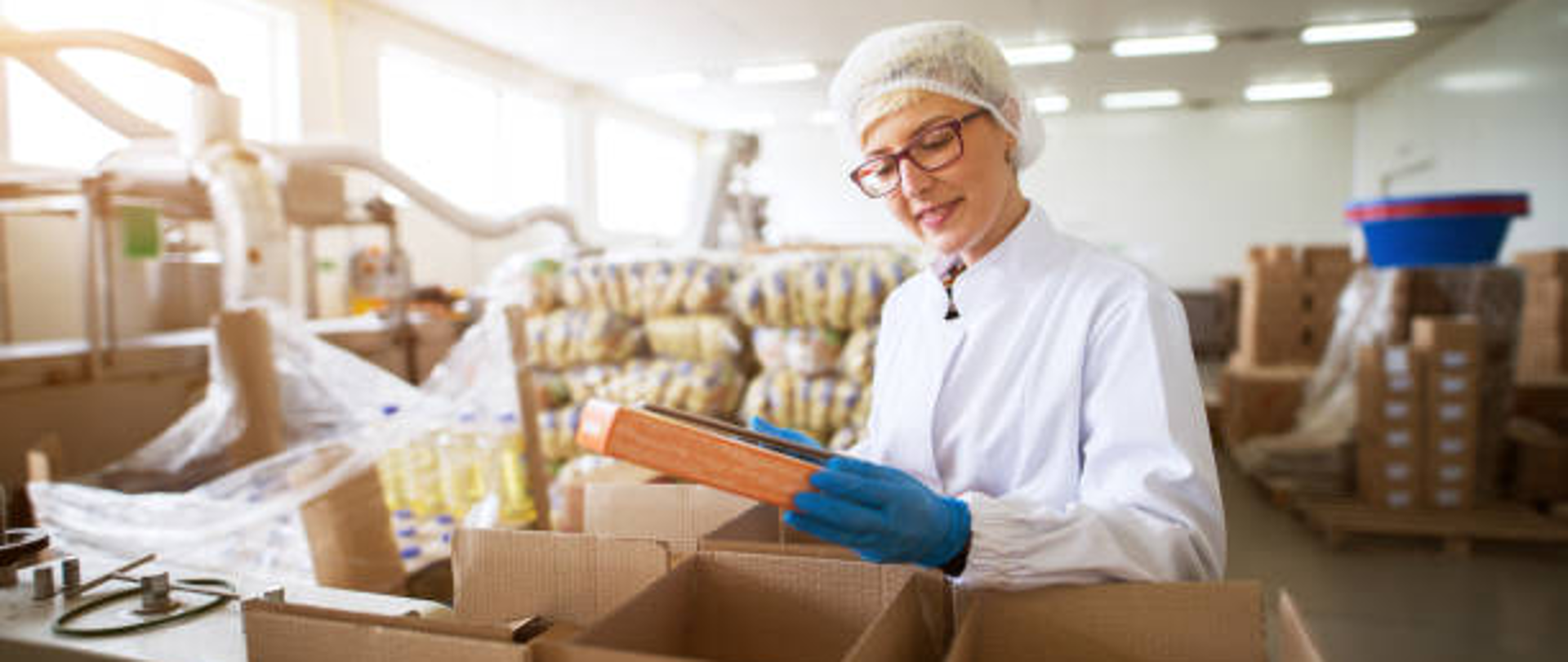 kobieta w okularach w magazynie z kartonami i środkami spożywczymi 