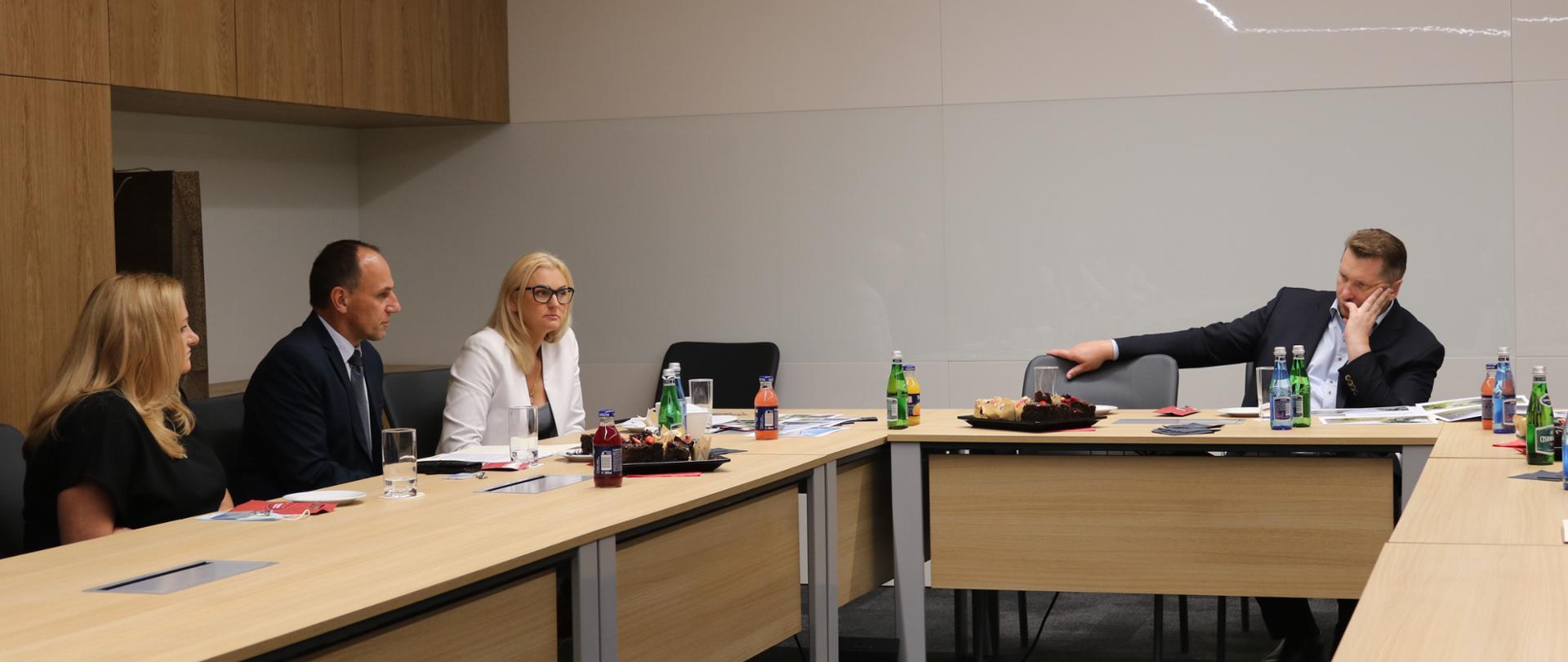 Ludzie siedzący przy stole w pomieszczeniu. Jedną z osób jest minister edukacji i nauki Przemysław Czarnek
