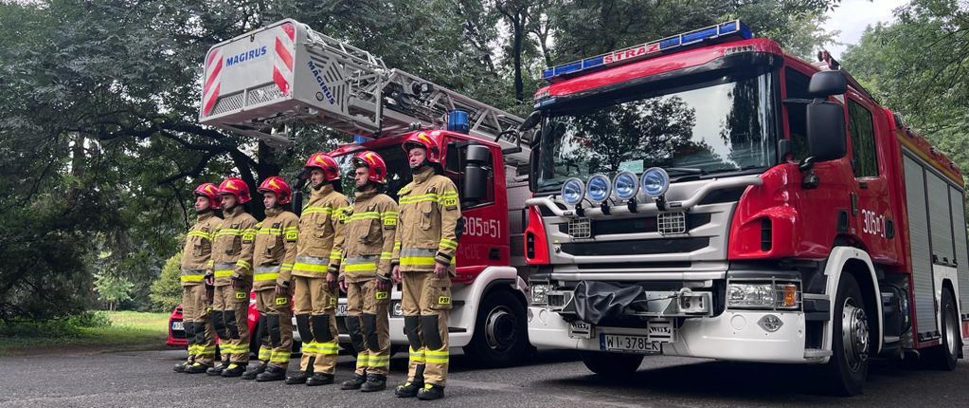 Na tle pojazdów PSP z JRG5 widać strażaków w ubraniach specjalnych i hełmach