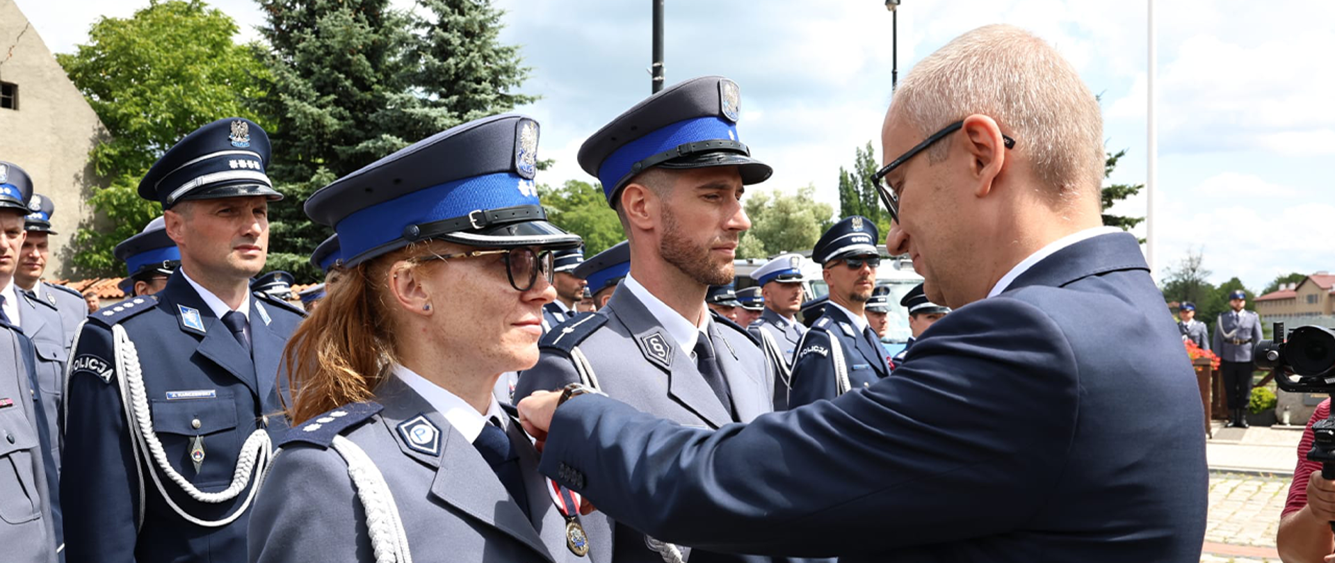 Wiceminister Błażej Poboży wpinający medal w mundur policjantki.